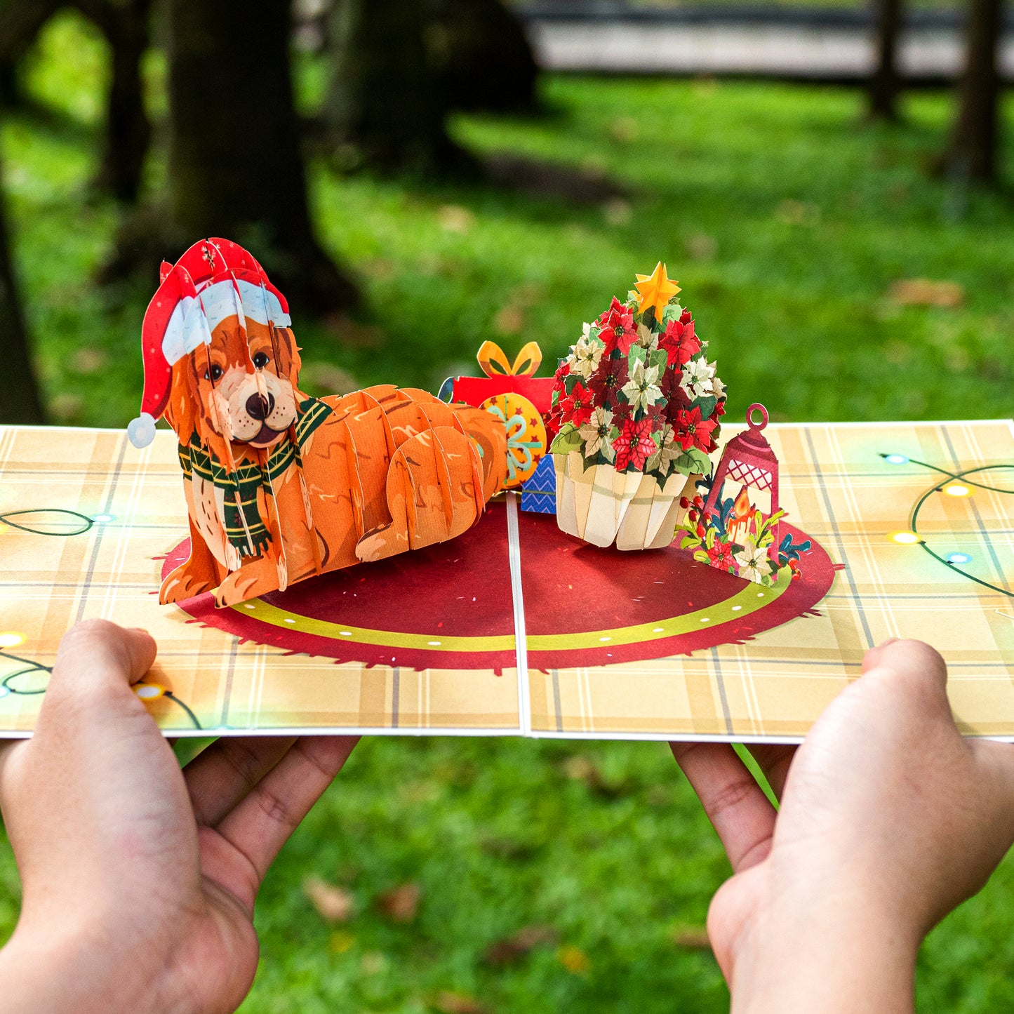 Hands holding a Christmas dog pop-up card with a festive dog and holiday decor.