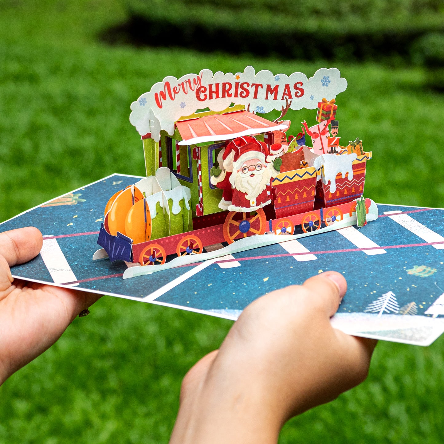 Hands holding Christmas Train Pop Up Card with intricate 3D design.