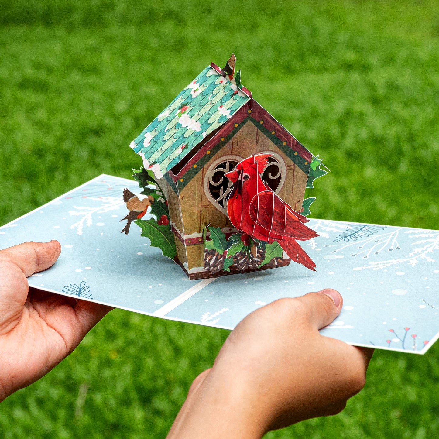 Hands holding the Love Bird House pop-up Christmas card showcasing its intricate 3D design.