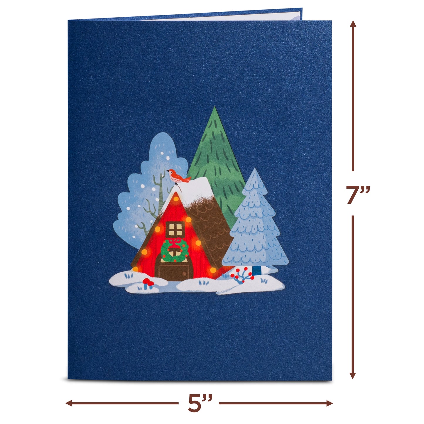 Closed Magical Town Christmas pop-up card with a cozy cabin illustration on a blue cover.