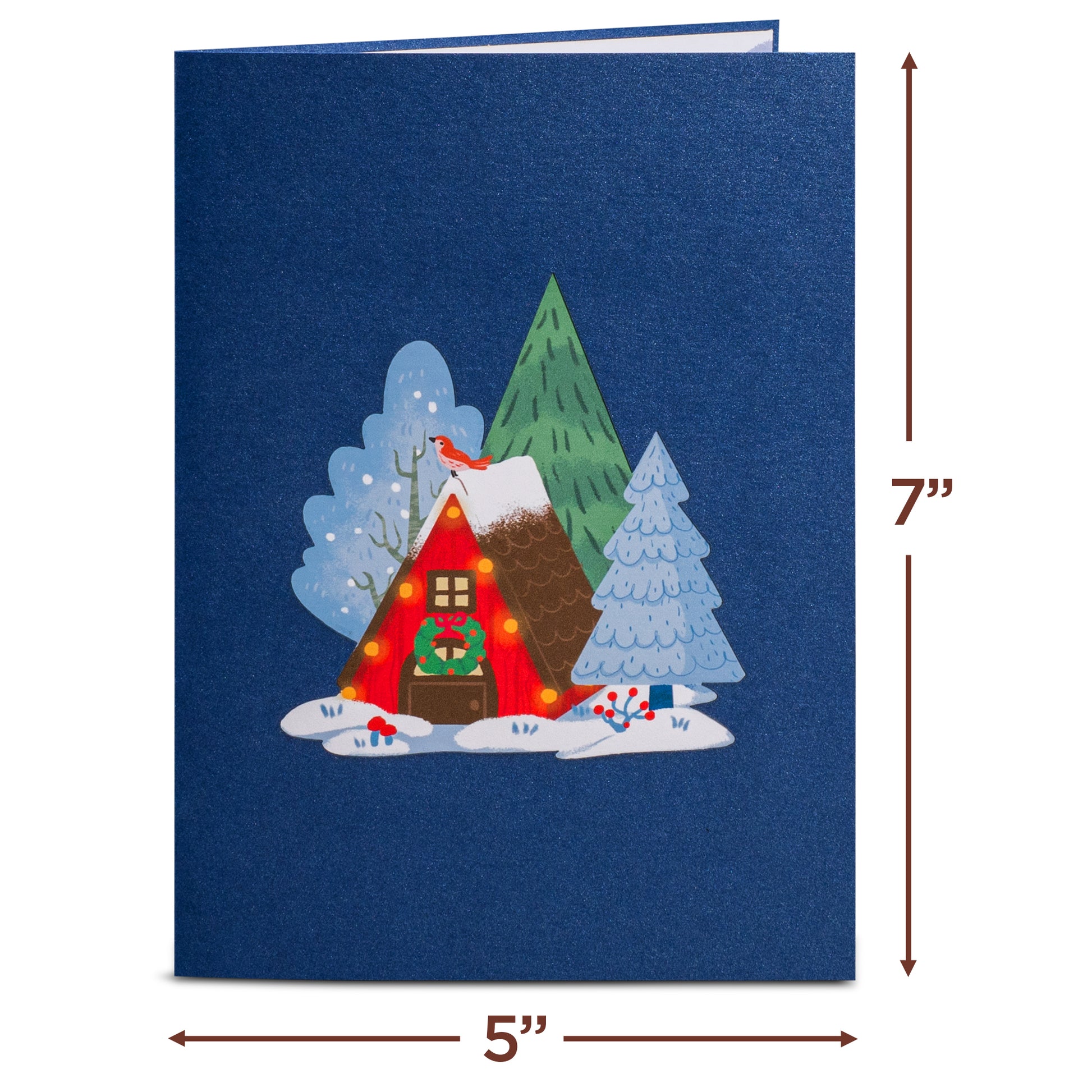 Closed Magical Town Christmas pop-up card with a cozy cabin illustration on a blue cover.