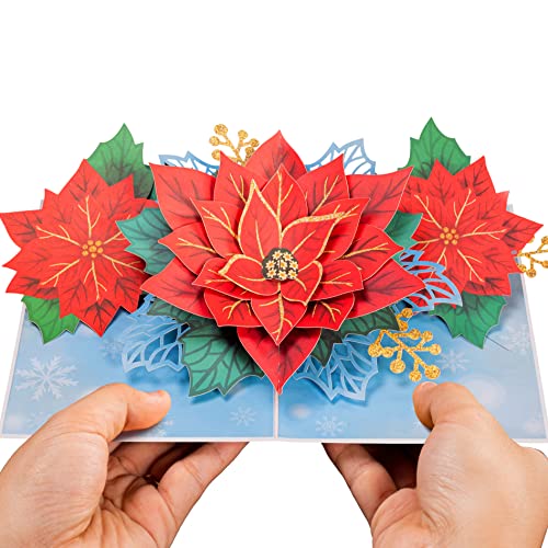 Hands holding a poinsettia pop-up Christmas card with intricate red flowers and gold accents.