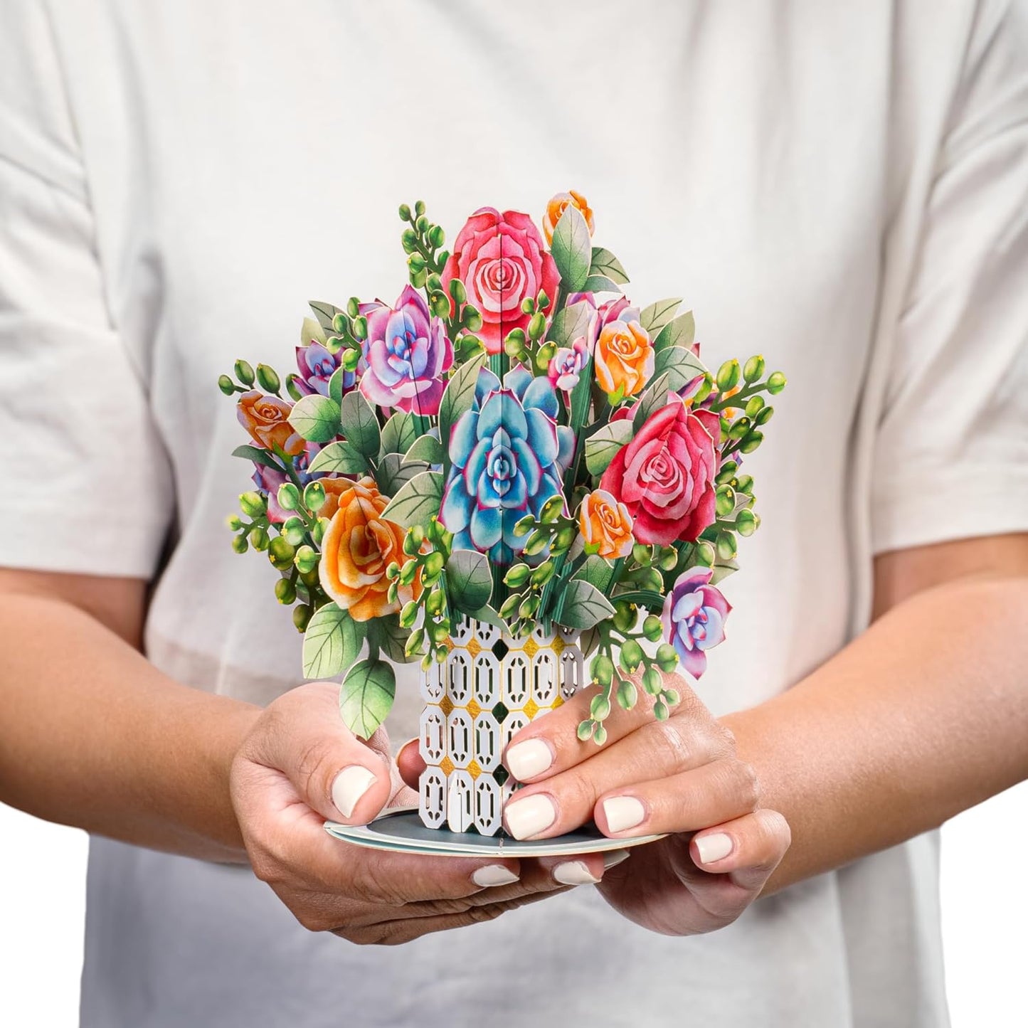 Person holding a colorful roses and succulent pop-up card with intricate details.