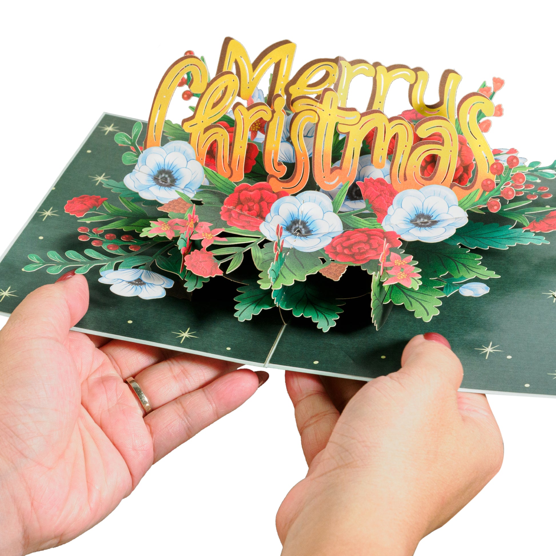 Hands opening a Merry Christmas pop-up card with floral arrangement inside.