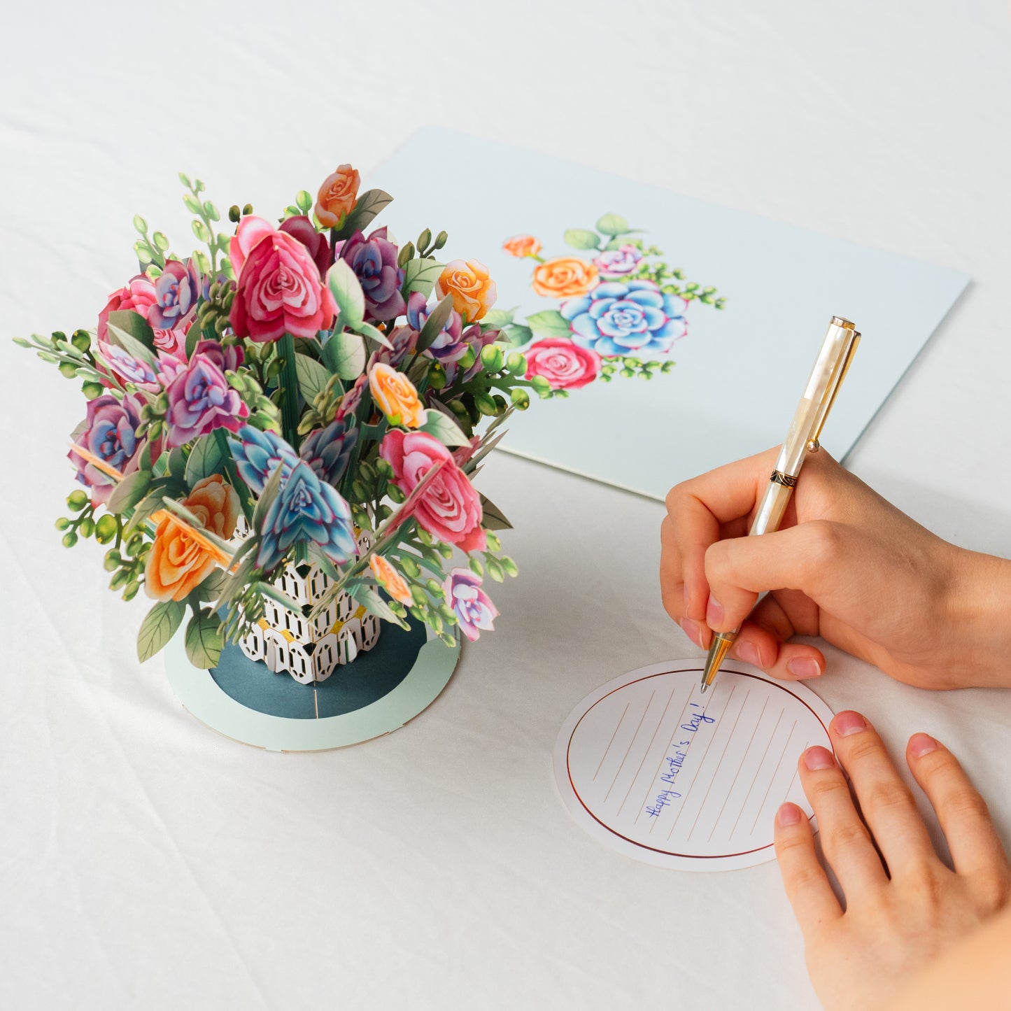 Pop-up card with roses and succulents alongside a removable note card being written on.