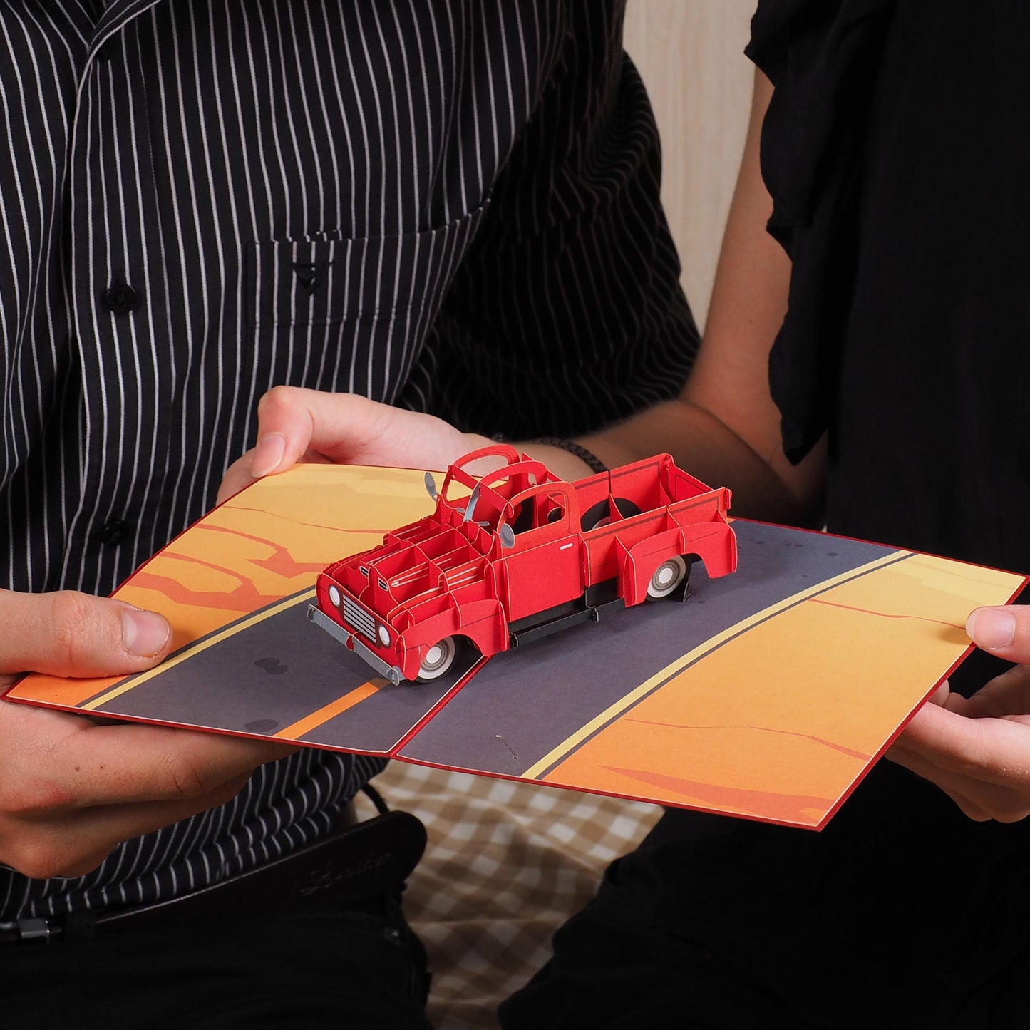 Two people holding the open Classic Truck Pop Up Card featuring a 3D red vintage truck.