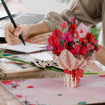 Filling out notecards with open flower bouquet pop up card