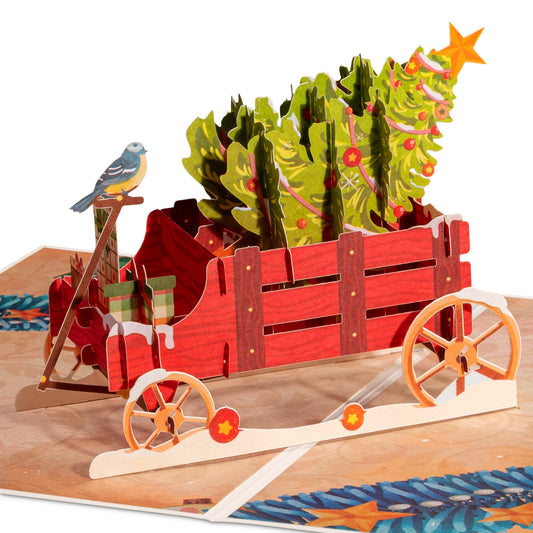 Pop-up Christmas card featuring a red wagon with a Christmas tree and bird.