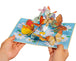 Hands holding a pop-up card featuring colorful butterflies and flowers.