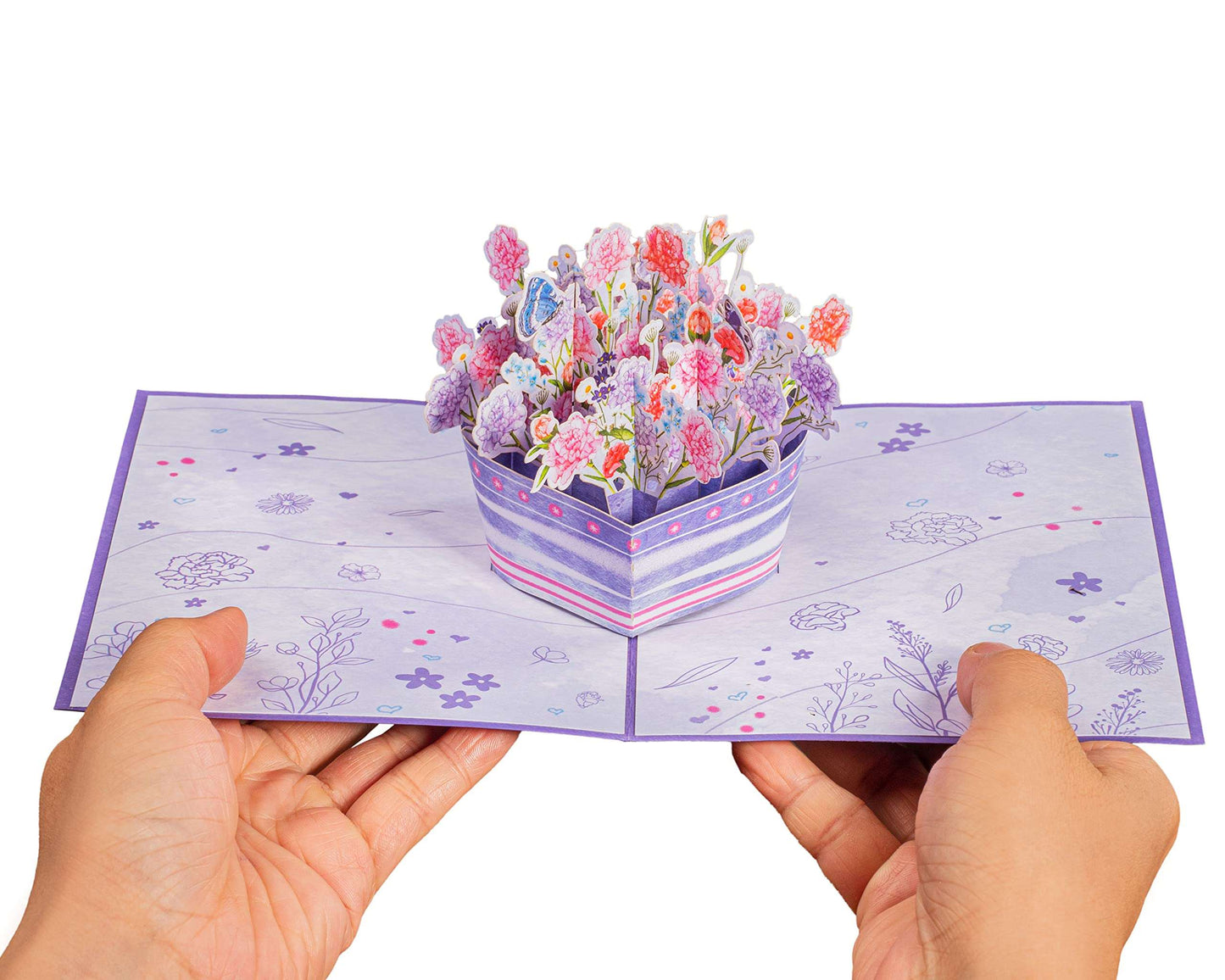 Hands holding a purple flowers pop-up card with intricate floral details.